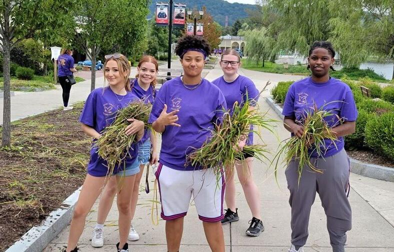 Students pose with weeds they pulled as part of their 社区服务 at Eldridge Park.