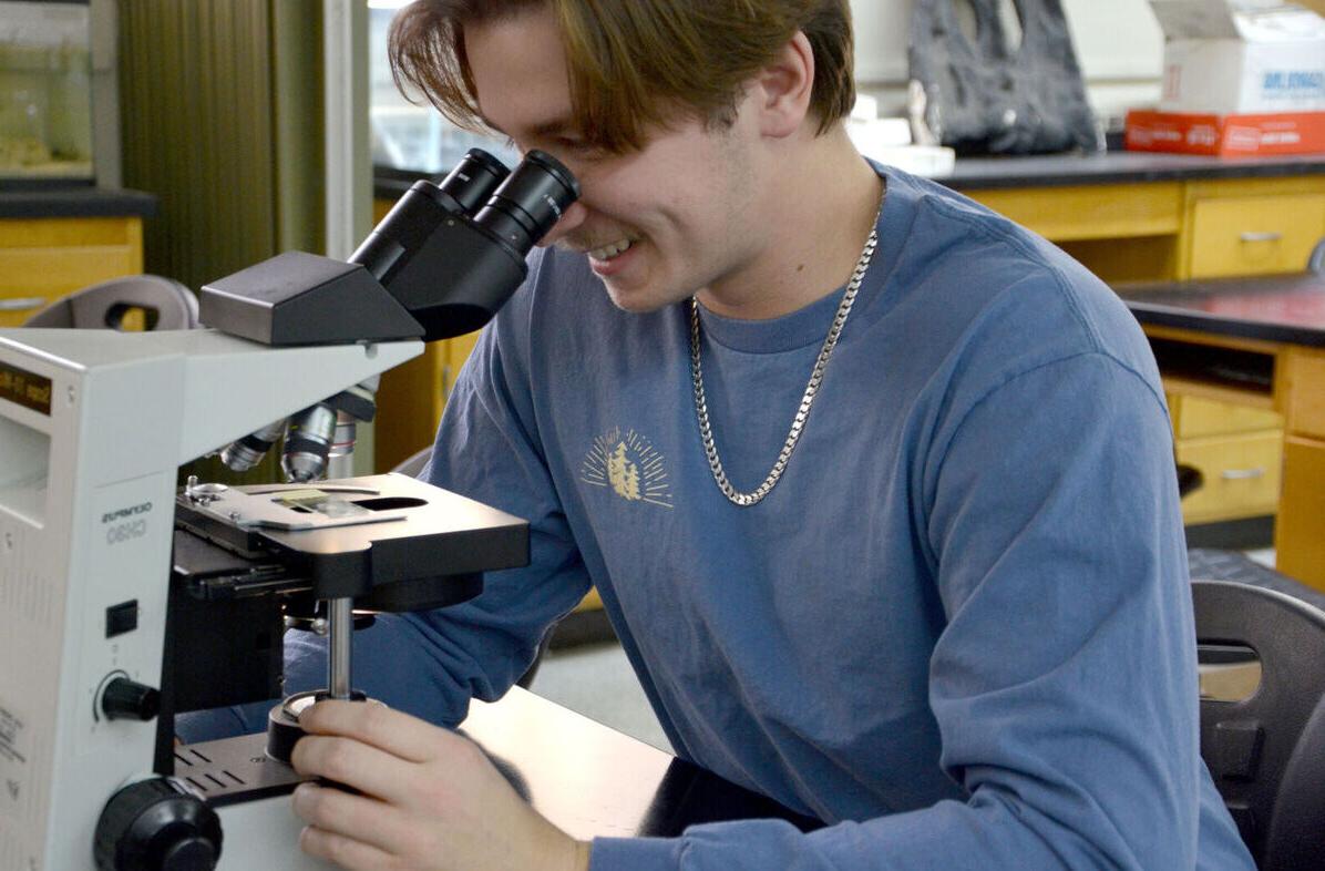 一位男学生通过显微镜观察